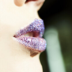 Nahaufnahme lila Glitzer auf den Lippen einer Frau - CAIF05538