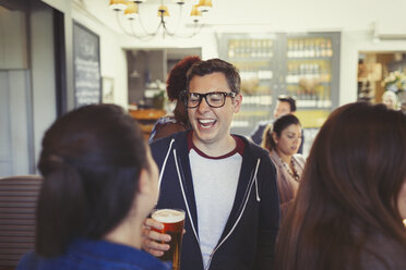 Mann lacht und trinkt Bier mit Freunden an der Bar - CAIF05542