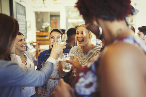Enthusiastische Freundinnen stoßen mit Weingläsern an der Bar an - CAIF05546