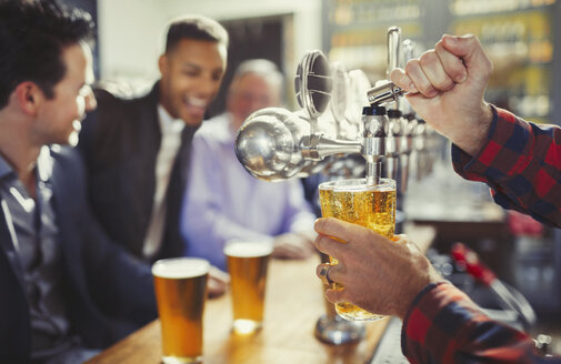 Barkeeper schenkt Bier aus dem Zapfhahn hinter der Bar ein - CAIF05549
