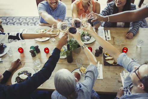 Overhead view friends toasting wine glasses at restaurant table - CAIF05550