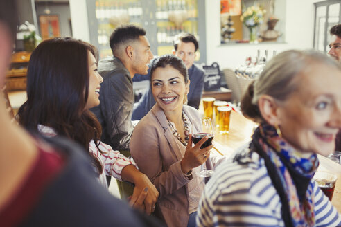 Lächelnde Frauen, die sich in einer Bar unterhalten und Wein trinken - CAIF05556