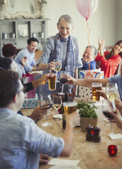 Freunde stoßen mit Wein- und Biergläsern auf einer Geburtstagsfeier im Restaurant an - CAIF05557