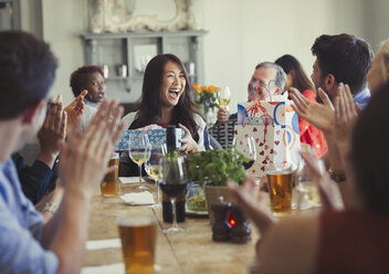 Freunde klatschen für eine glückliche Frau, die am Restauranttisch Geburtstag feiert - CAIF05562