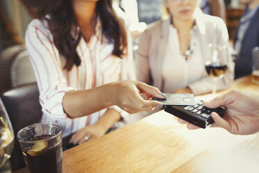 Frau bezahlt Barkeeper mit kontaktloser Kreditkarte an der Bar - CAIF05567