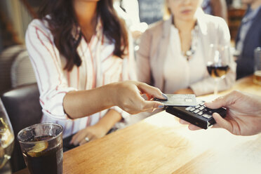 Woman paying bartender with credit card contactless payment at bar - CAIF05567