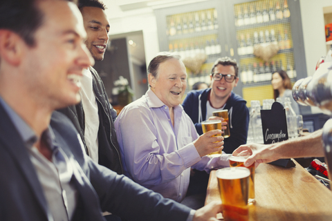 Lächelnde Männer, die an einer Bar Bier trinken, lizenzfreies Stockfoto