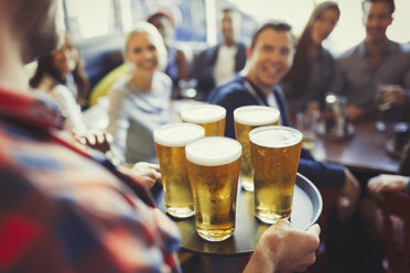 Barkeeper serviert Freunden in einer Bar ein Tablett mit Bieren - CAIF05570