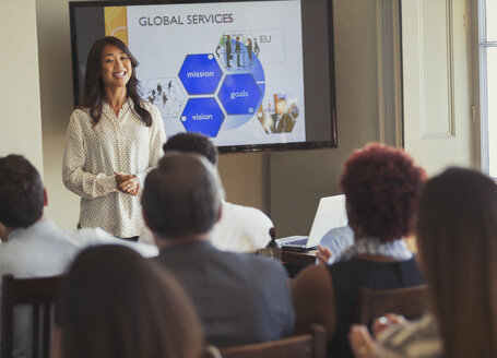 Lächelnde Geschäftsfrau, die eine Präsentation auf einer Geschäftskonferenz vor einem Fernsehbildschirm leitet - CAIF05571