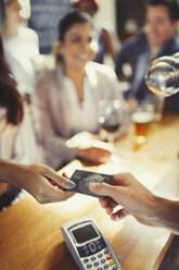 Frau bezahlt Barkeeper mit Kreditkarte an der Bar - CAIF05574
