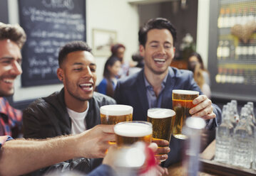 Men friends toasting beer glasses at bar - CAIF05580