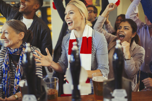 Begeisterte Sportfans, die an der Bar jubeln und das Spiel verfolgen - CAIF05595