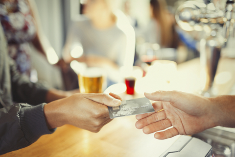 Frau bezahlt Barkeeper mit Kreditkarte an der Bar, lizenzfreies Stockfoto