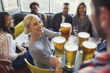 Barkeeper serviert Bier auf einem Tablett an Freunde in einer Bar - CAIF05605