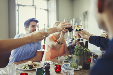 Freunde feiern, stoßen mit Weingläsern an und speisen am Restauranttisch - CAIF05618