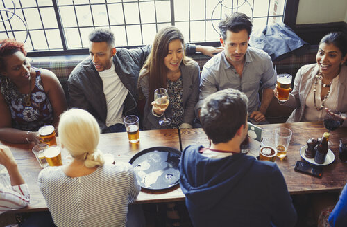 Blick von oben auf Freunde, die an einem Tisch in einer Bar Bier und Wein trinken - CAIF05624