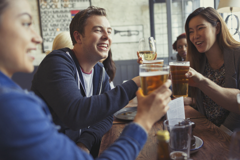 Freunde feiern, stoßen mit Bier- und Weingläsern am Tisch in der Bar an, lizenzfreies Stockfoto