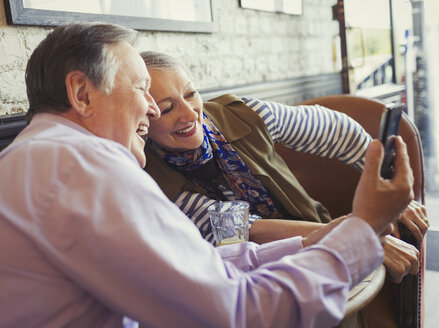 Lächelndes älteres Paar, das ein Selfie mit einem Fotohandy am Kaffeetisch macht - CAIF05627