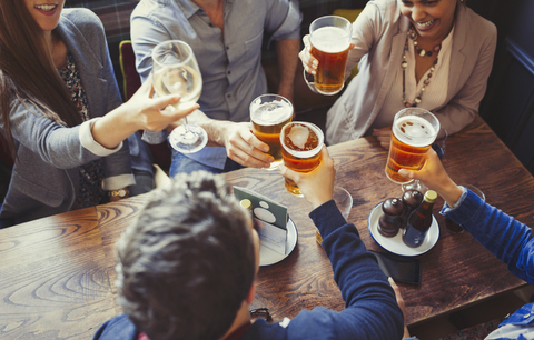 Overhead view friends celebrating, toasting beer and wine glasses at table in bar stock photo