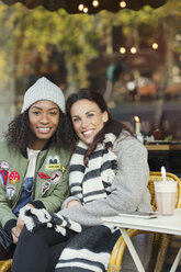 Porträt lächelnd junge Frauen Freunde in warmer Kleidung am Bürgersteig Cafe - CAIF05648
