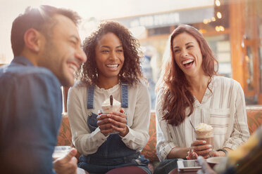 Lachende junge Freunde trinken Milchshakes in einem Cafe - CAIF05656