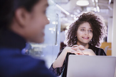 Smiling businesswoman at laptop listening in conference room meeting - CAIF05671