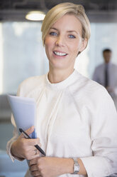 Porträt einer lächelnden, selbstbewussten Geschäftsfrau mit Papierkram - CAIF05676