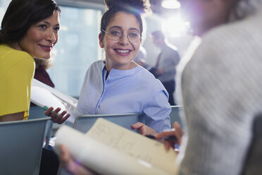 Lächelnde Geschäftsfrauen, die im Konferenzsaal über Papierkram diskutieren - CAIF05690