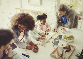 Multiethnische junge Familie, die am Tisch mit Stiften malt - CAIF05709