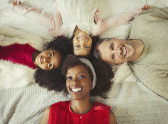 Overhead-Porträt lächelnde multiethnische junge Familie auf dem Bett liegend - CAIF05715