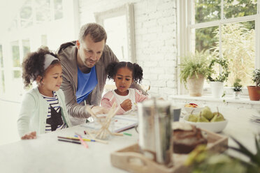 Multiethnischer Vater und Töchter beim Färben in der Küche - CAIF05724