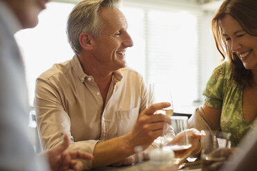 Smiling mature couple drinking wine, dining at restaurant table - CAIF05746