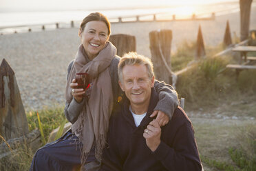Porträt lächelnd reifes Paar hält Hände und trinken Wein auf Sonnenuntergang Strand - CAIF05756