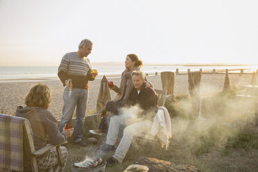 Ältere Paare trinken Wein und grillen am Strand bei Sonnenuntergang - CAIF05764
