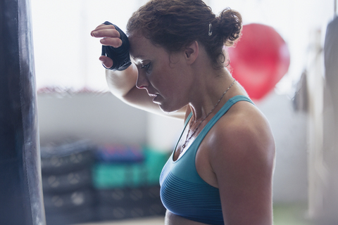 Müder weiblicher Boxer wischt sich im Fitnessstudio den Schweiß von der Stirn, lizenzfreies Stockfoto