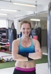 Porträt einer selbstbewussten, lächelnden Boxerin im Fitnessstudio - CAIF05779