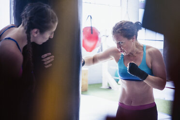 Entschlossene, zähe Boxerinnen boxen im Fitnessstudio am Sandsack - CAIF05781