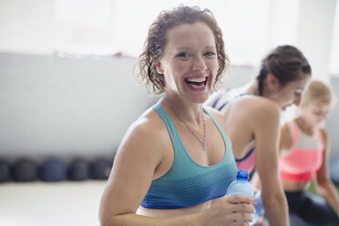 Portrait lächelnde, lachende Frau, die Wasser trinkt und sich nach dem Training im Fitnessstudio ausruht - CAIF05793