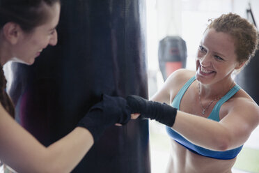 Lächelnde weibliche Boxerinnen, die sich im Fitnessstudio die Fäuste stoßen - CAIF05800