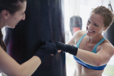 Smiling female boxers fist bumping in gym - CAIF05800