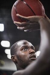 Nahaufnahme fokussierter junger männlicher Basketballspieler, der den Ball schießt - CAIF05843