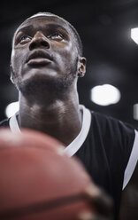 Nahaufnahme fokussierter junger männlicher Basketballspieler mit Basketball, der nach oben schaut - CAIF05849