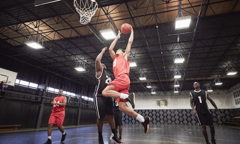 Junge männliche Basketballspieler spielen Basketball auf einem Platz in einer Sporthalle, lizenzfreies Stockfoto