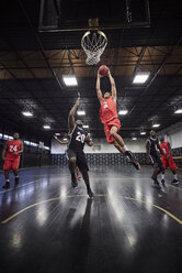 Junger männlicher Basketballspieler, der in einem Spiel in einer Sporthalle einen Basketball in die Luft wirft - CAIF05856