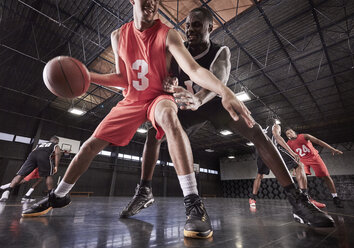 Junge männliche Basketballspieler spielen auf dem Platz in einer Turnhalle - CAIF05859