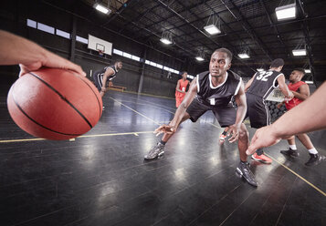 Junge männliche Basketballspieler spielen auf dem Platz in einer Turnhalle - CAIF05860