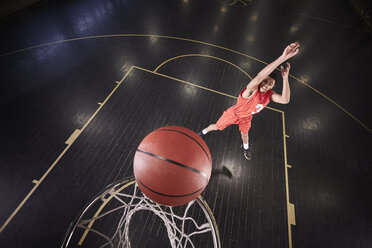 Young male basketball player shooting the ball on court in gymnasium - CAIF05861