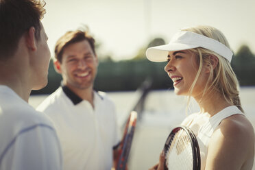 Männliche und weibliche Tennisspieler unterhalten sich auf dem Tennisplatz - CAIF05862