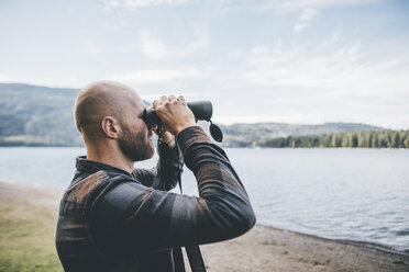 Kanada, British Columbia, Mann schaut durch ein Fernglas am Cultus Lake - GUSF00409
