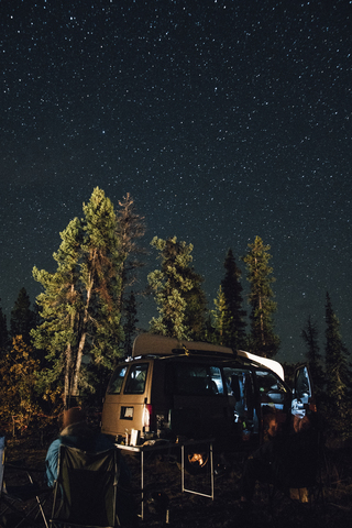 Kanada, British Columbia, zwei Männer sitzen unter dem Sternenhimmel in einem Minivan bei Nacht, lizenzfreies Stockfoto